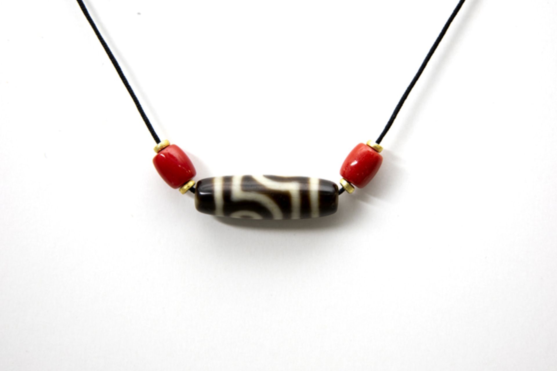 Himalayan dzi stone on a cord with two red beads Dzi - steen uit de Himalya met een mooie