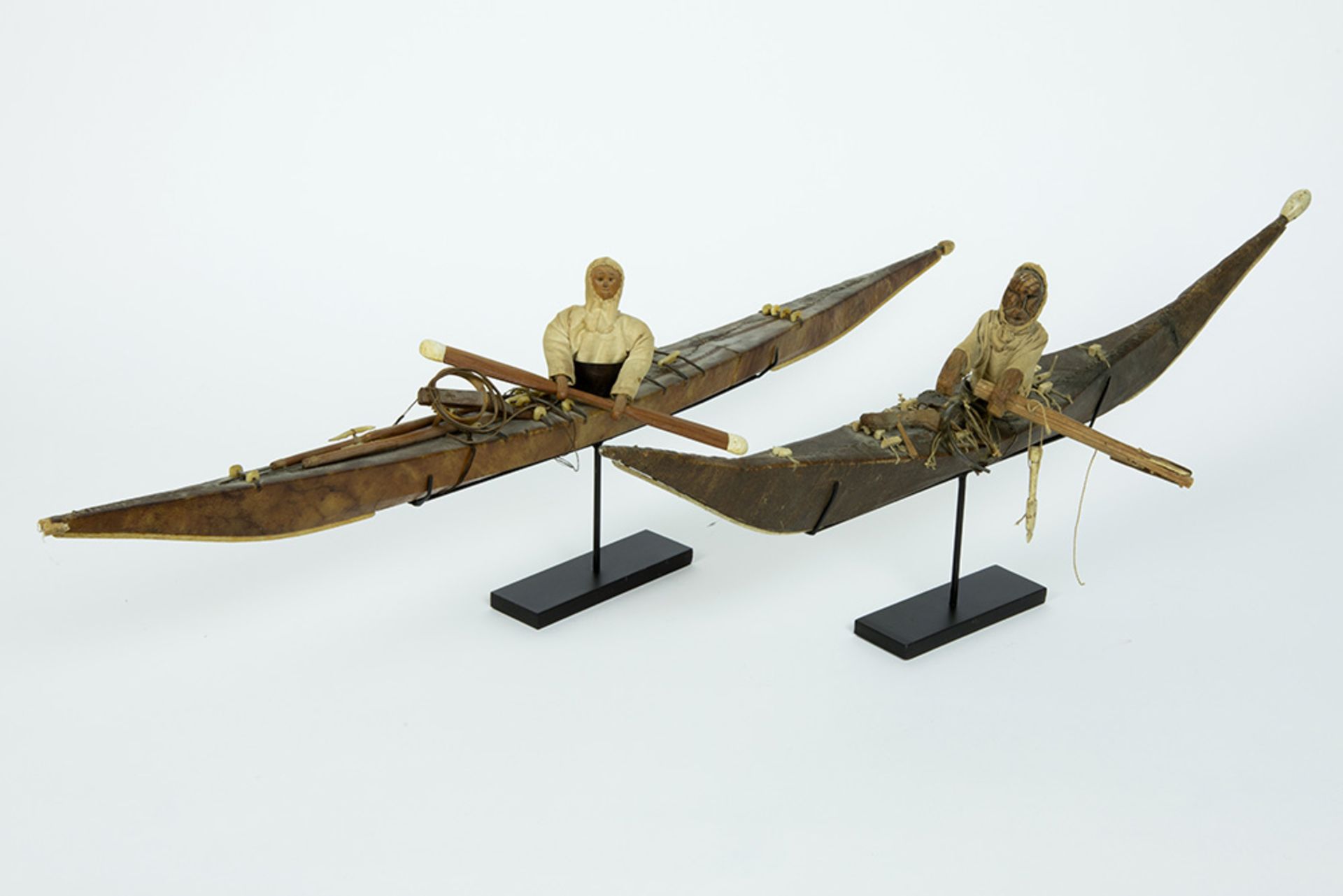 two antique Greenland Inuit model kayaks in wood covered with seal skin - with a doll wearing a