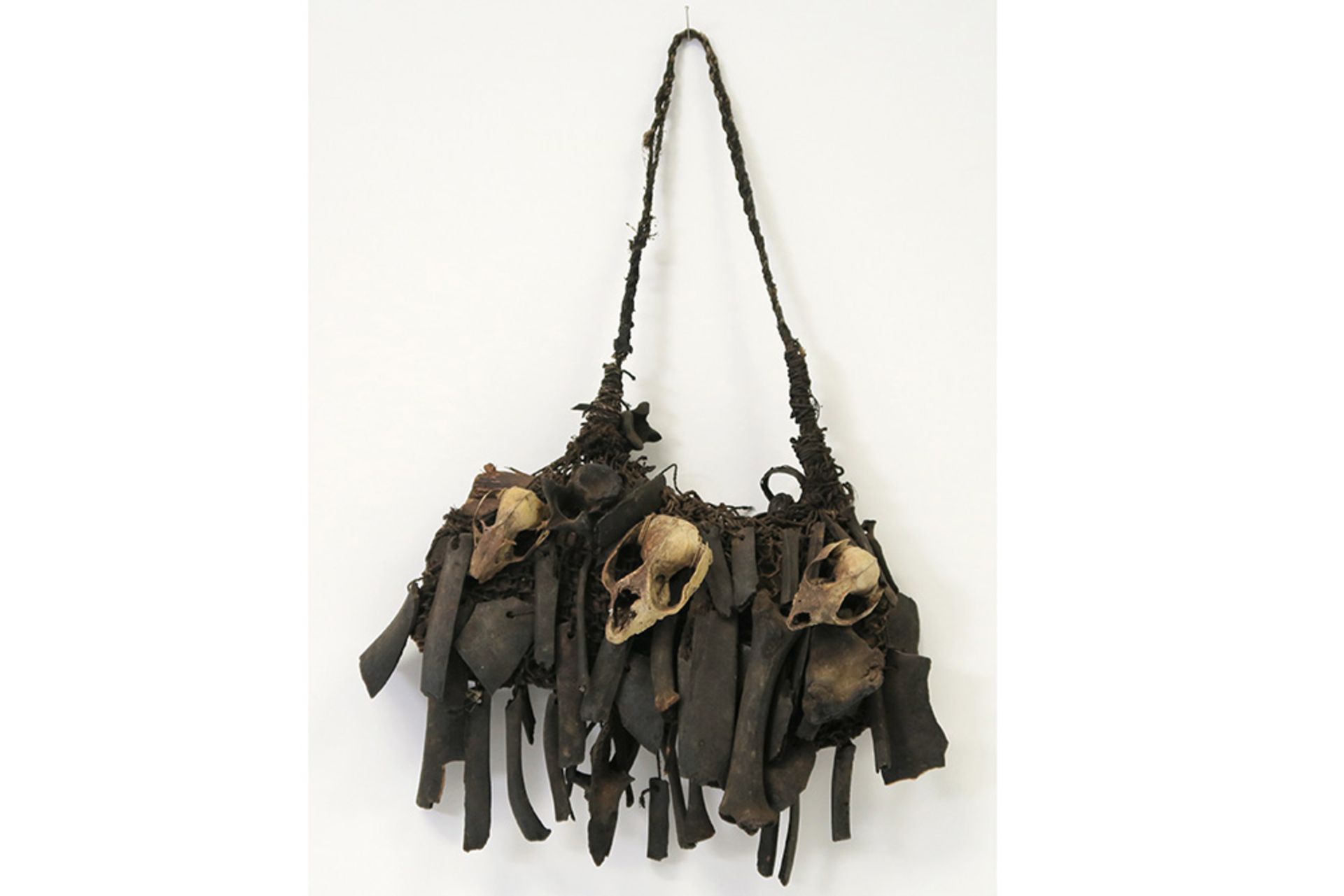 early 20th Cent. Papua New Guinean Asmat magic hunting bag with bones and Marsipulami skulls ||