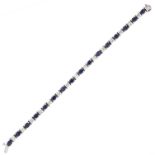 A SAPPHIRE AND DIAMOND BRACELET in 14ct white gold, comprising a single row of sixteen oval cut blue