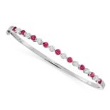 RUBY AND DIAMOND BANGLE of plain hoop design, hinged, set to one side with alternating round cut