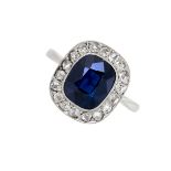 A SAPPHIRE AND DIAMOND CLUSTER RING set with a cushion cut sapphire of 3.13 carats in a border of
