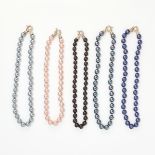 A MIXED LOT OF FIVE FAUX PEARL NECKLACES comprising of a single row of purple, grey, pink, black and