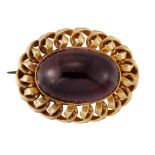 A VICTORIAN GARNET BROOCH, an oval cabochon garnet in a rub-over setting within a scroll frame, with