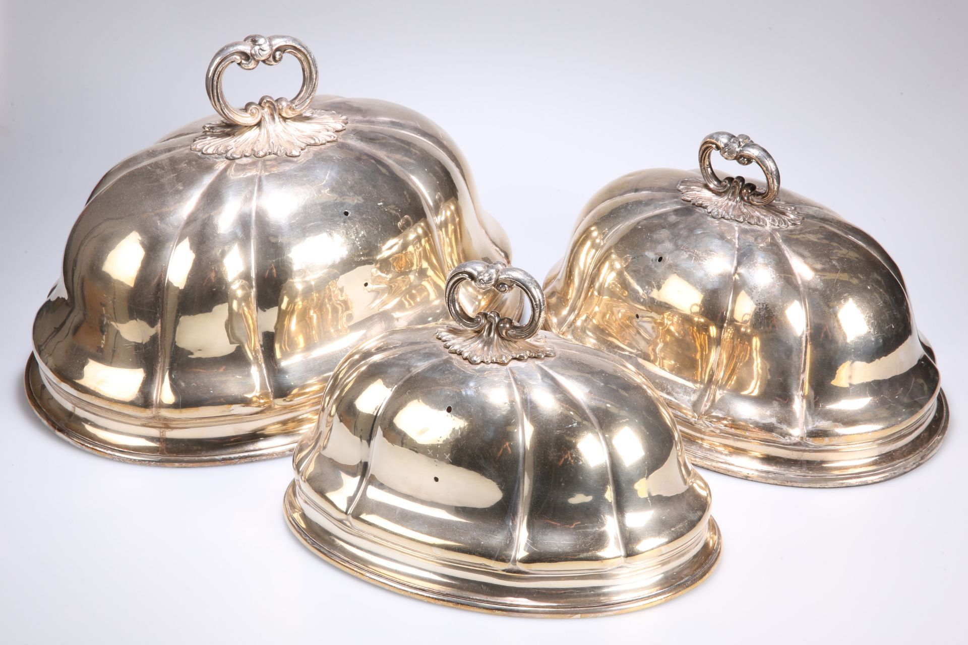 ^ A GRADUATED SET OF THREE SILVER-PLATED MEAT COVERS