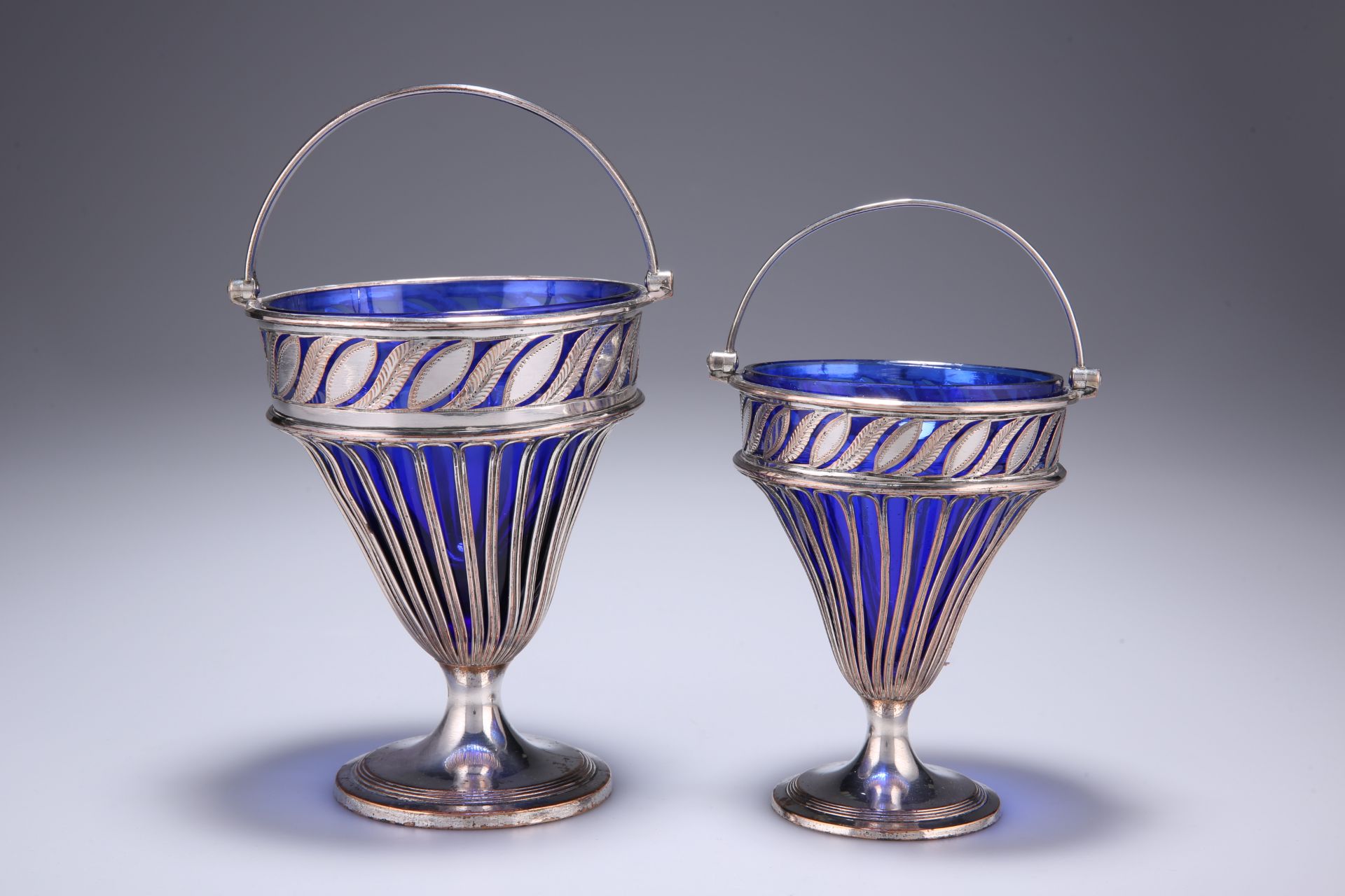 A GRADUATED PAIR OF OLD SHEFFIELD PLATED SWING-HANDLED BASKETS