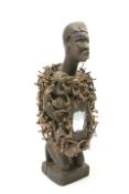 A carved tribal figure embellished with nails and mirror glass to the front, 38cm high