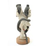 A tribal double headed figure group, the breasted figure clutching a snake, 61cm high