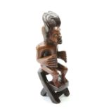 A tribal carved figure group, the seated figure modelled seated on a chair, 56cm high
