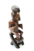 A tribal carved figure group, the seated figure modelled seated on a chair, 56cm high