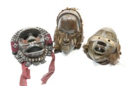 Three tribal masks including one embellished with shells