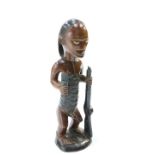 A carved tribal figure modelled holding a staff, 49cm high