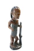 A carved tribal figure modelled holding a staff, 49cm high