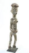 A large carved tribal figure on an iron stand, 75cm high overall
