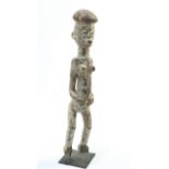 A large carved tribal figure on an iron stand, 75cm high overall