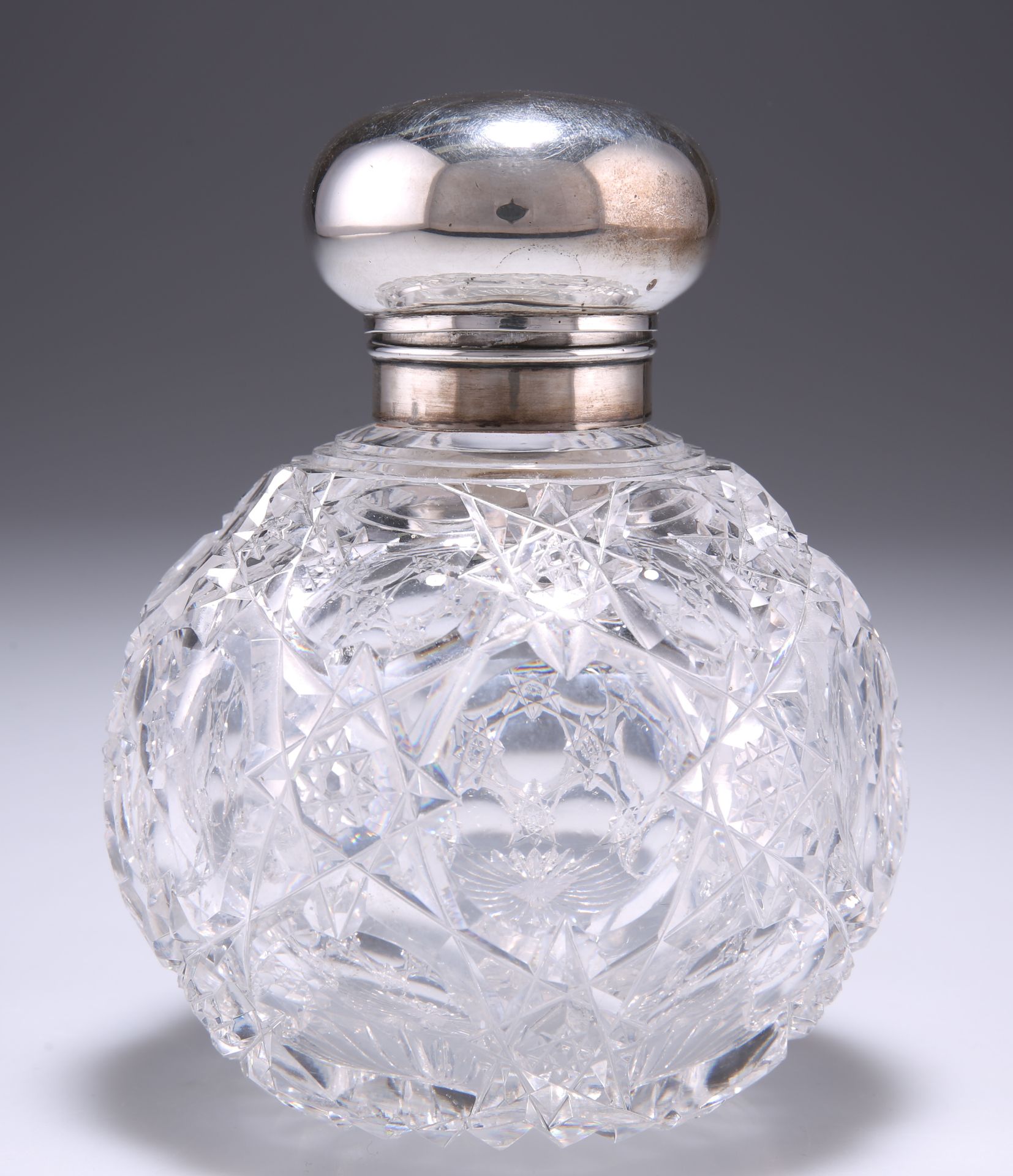 AN EDWARDIAN SILVER-TOPPED CUT-GLASS SCENT BOTTLE