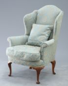 A WALNUT AND UPHOLSTERED WINGBACK ARMCHAIR