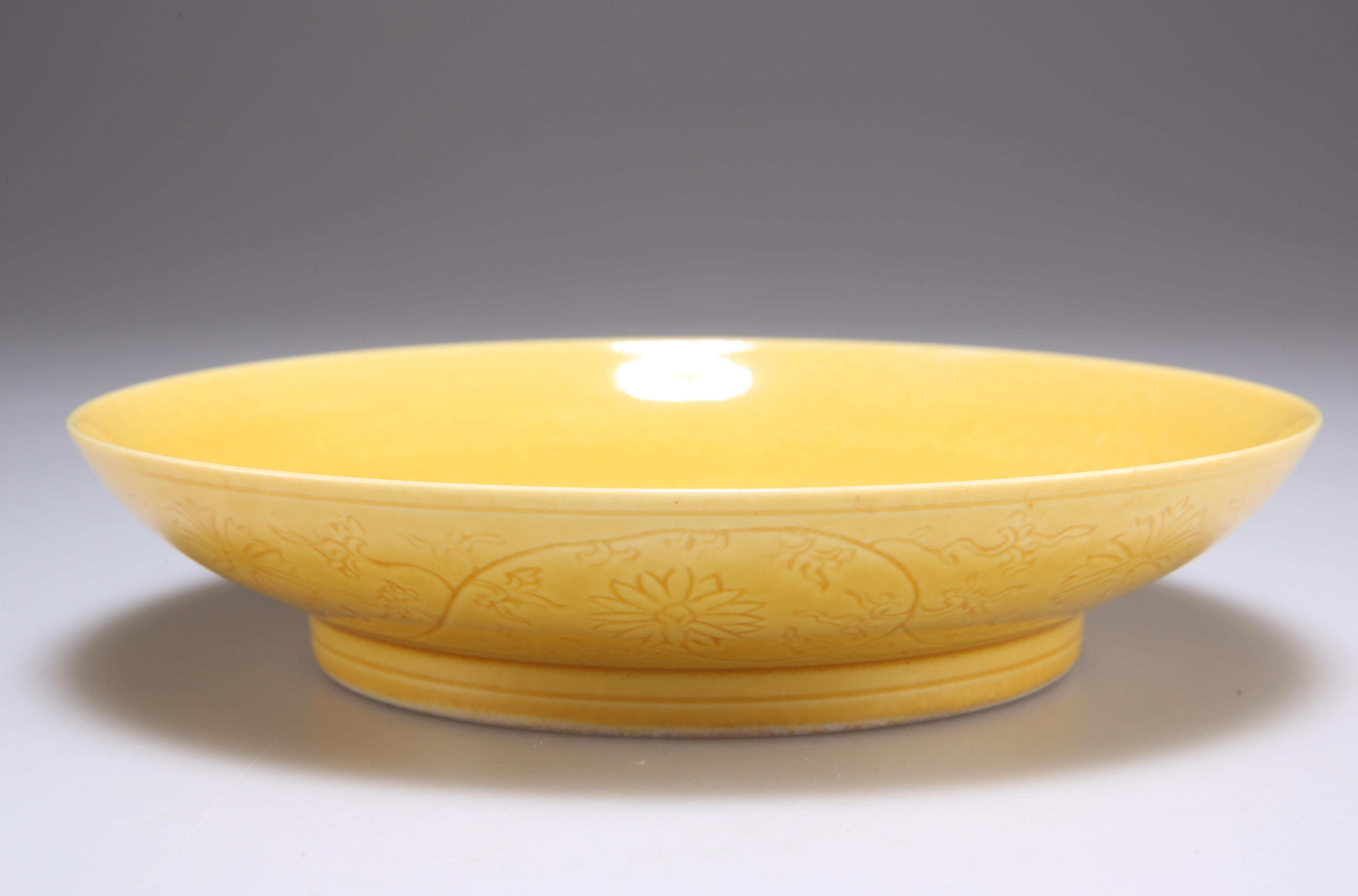 A CHINESE YELLOW-GLAZED PORCELAIN SAUCER DISH
