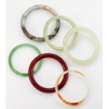 A GROUP OF FIVE JADE AND OTHER HARDSTONE BANGLES AND A GREEN GLASS BANGLE