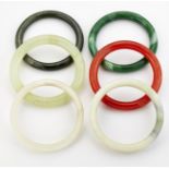 A GROUP OF FIVE JADE AND OTHER HARDSTONE BANGLES AND A GREEN GLASS BANGLE