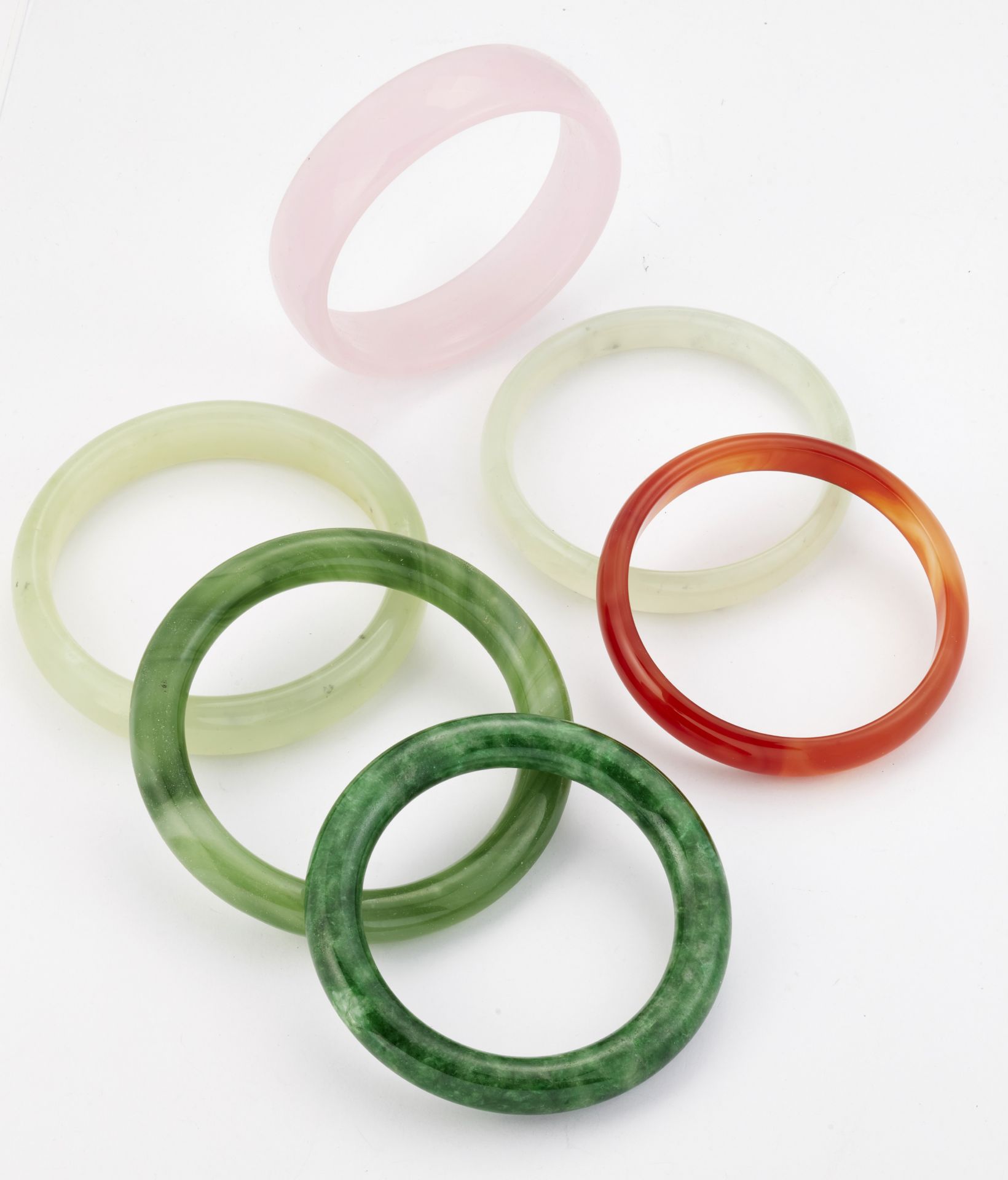 A GROUP OF FIVE JADE AND OTHER HARDSTONE BANGLES AND A GREEN GLASS BANGLE