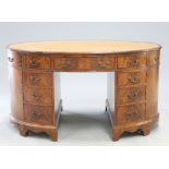 A GEORGE III STYLE LEATHER INSET MAHOGANY OVAL PARTNERS DESK