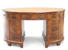 A GEORGE III STYLE LEATHER INSET MAHOGANY OVAL PARTNERS DESK