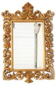 A LARGE BAROQUE STYLE GILT COMPOSITION MIRROR