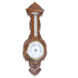 AN EDWARDIAN CARVED OAK ANEROID BAROMETER