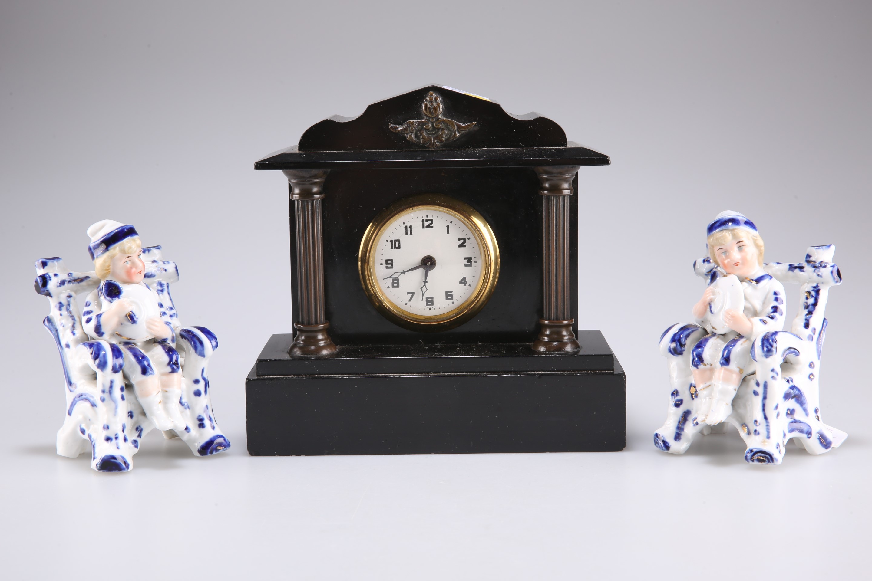 Two pressed porcelain figures of boys and a black slate mantel clock