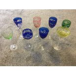 Eight mixed Bohemian coloured and hand cut crystal glasses.