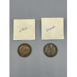 Two old pennies with double head and tails sides.