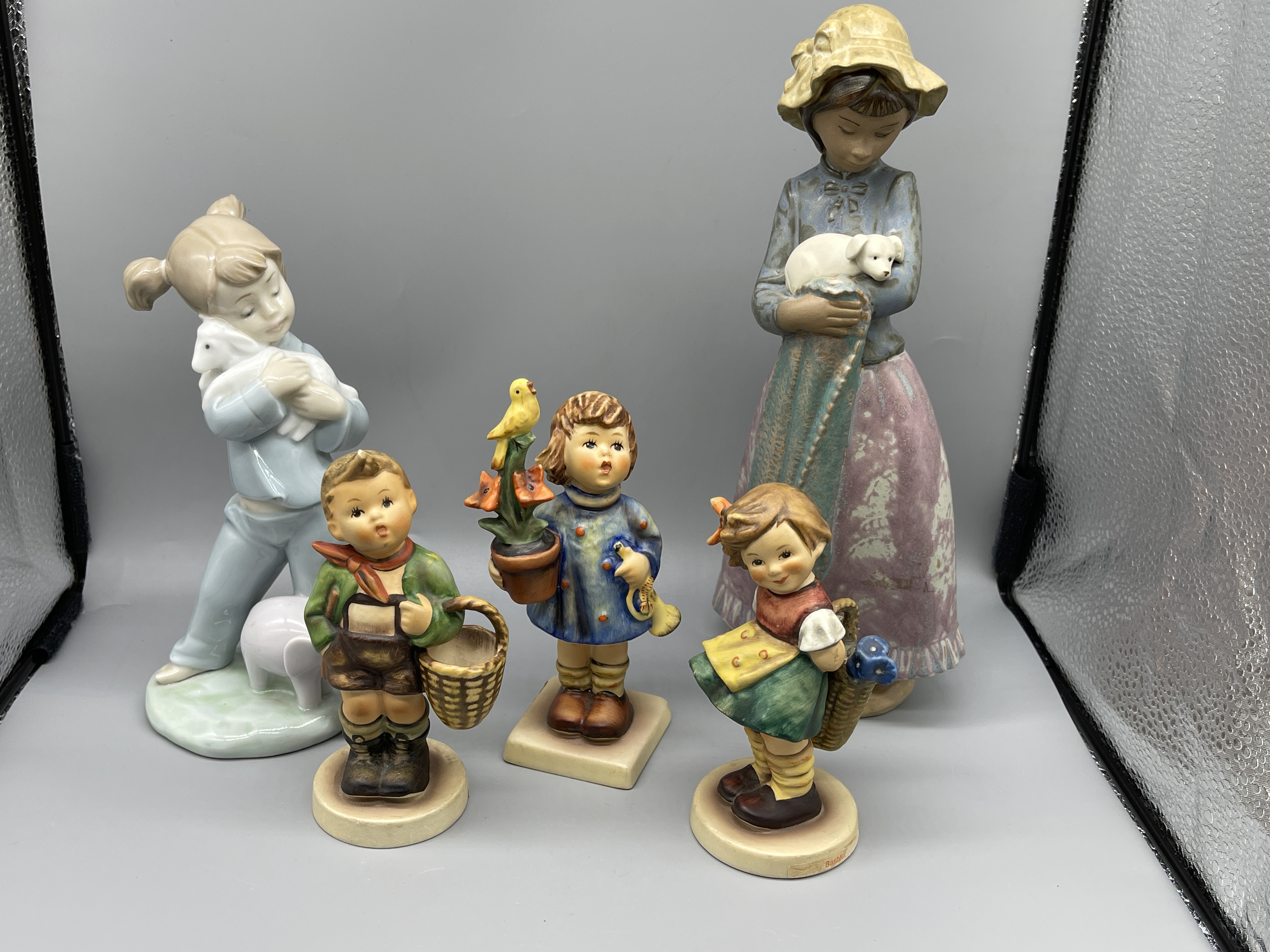 Two Nao figurines and three hummel figurines.