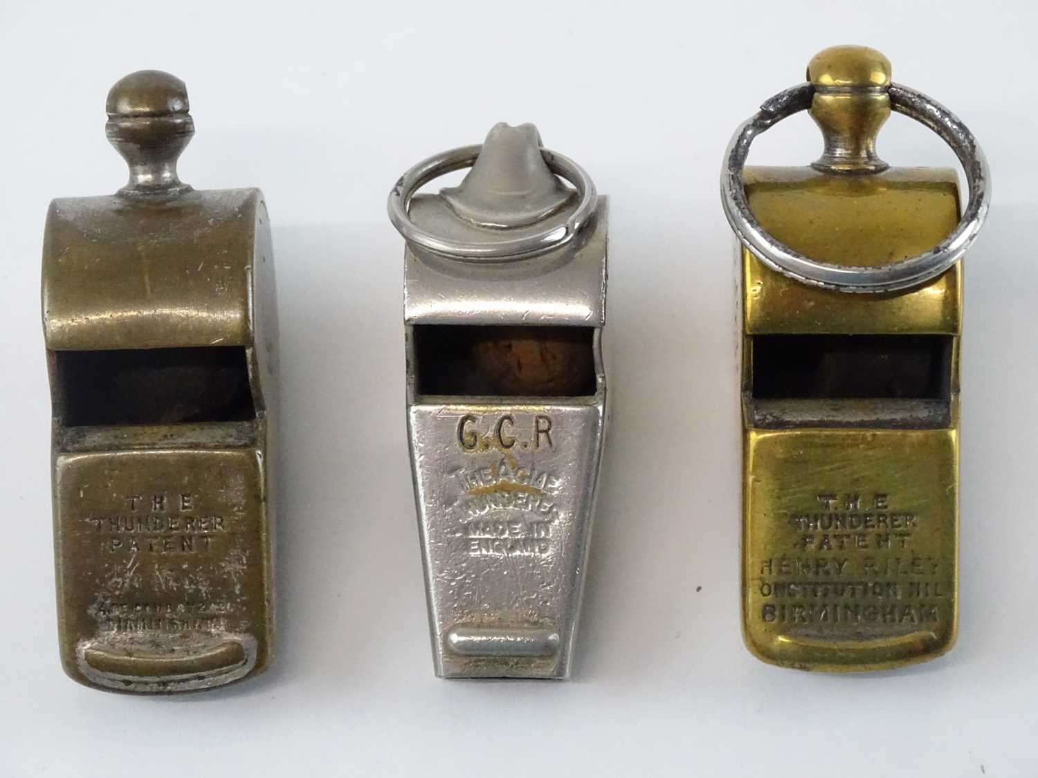 A group of Thunderer Patent whistles comprising two brass and one nickel plated example - all