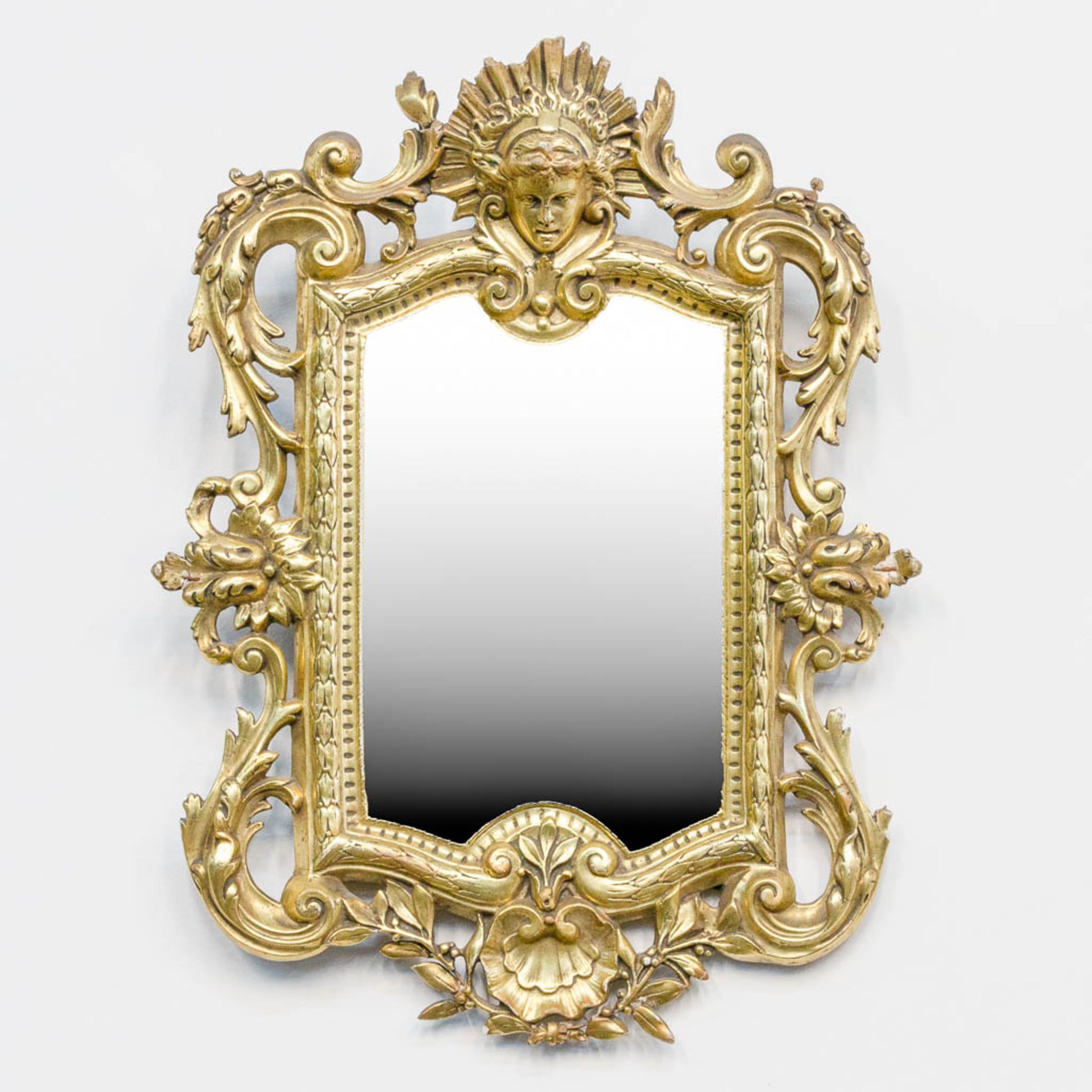 A mirror in Louis XV style, made of gold plated stuco.
