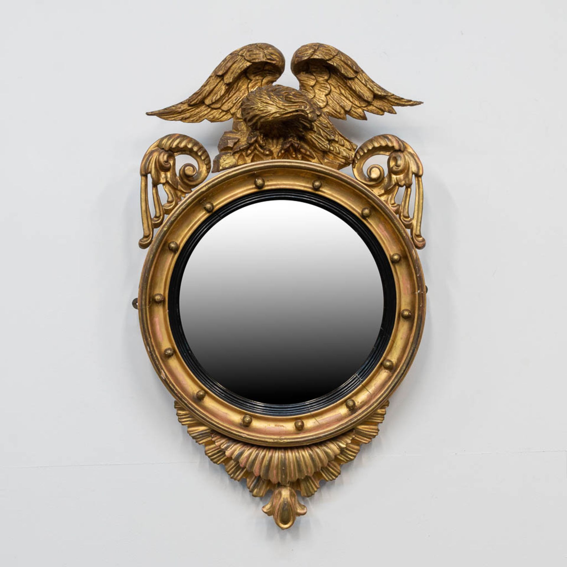 A round mirror, made of sculptured wood, decorated with an Eagle.