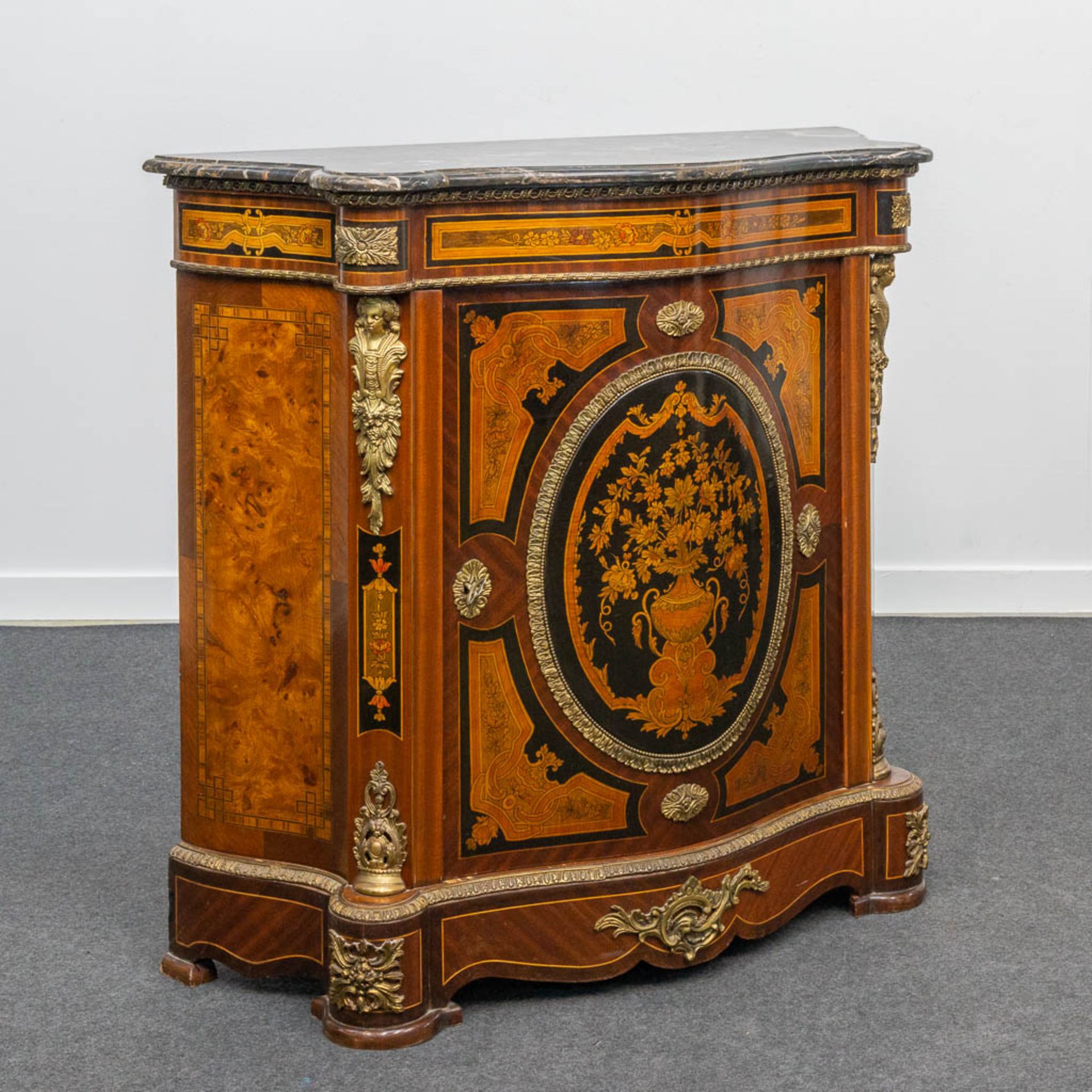 A marquetry inlaid commode, mounted with bronze and with a marble top.