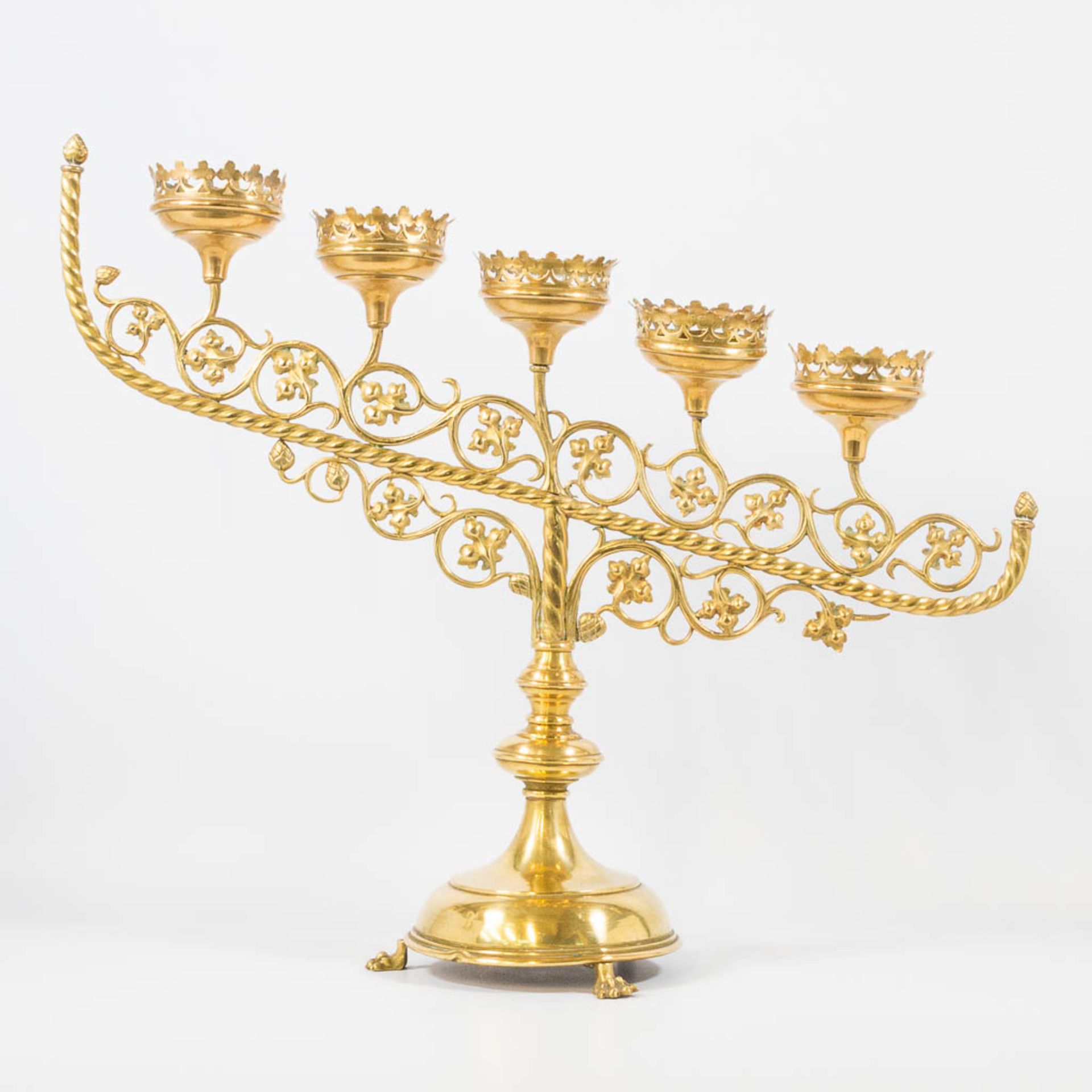 An Antique brass church candelabra, decorated with grape vine leaves and standing on claw feet, Fran