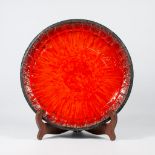 A display plate, made of ceramics with a red glaze, most likely made by Jan Nolf.
