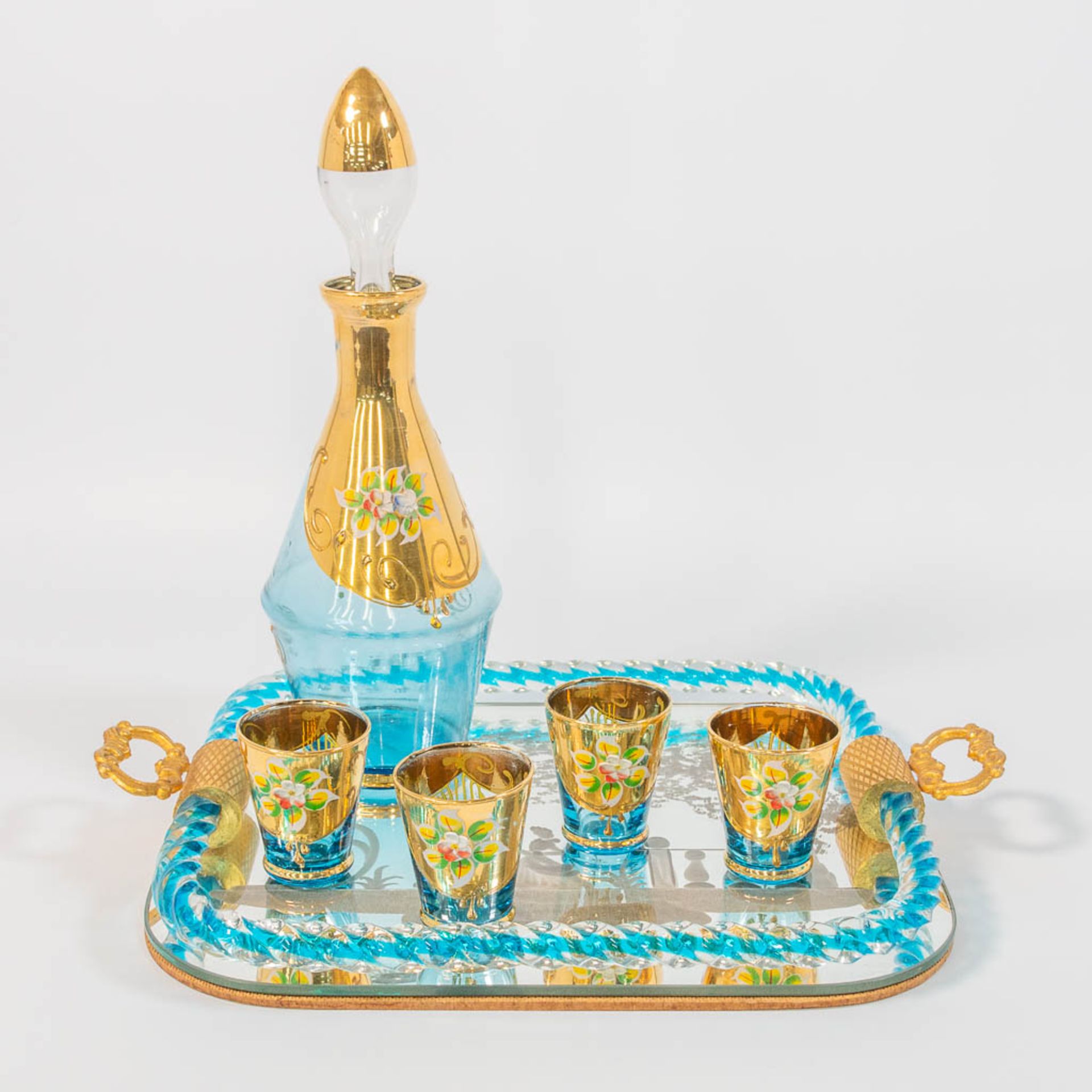 A decanter, glasses, and tray with gold painted flowers and etched decor.