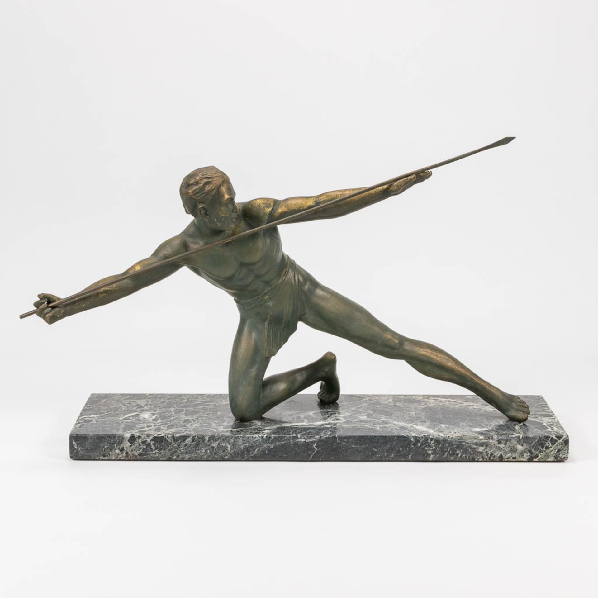 A bronze statue of a spear thrower in art deco style and standing on a marble base. The first half o