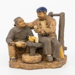 A Japanese terracotta statue of a couple having tea. Marked. (20 x 33 x 31 cm)