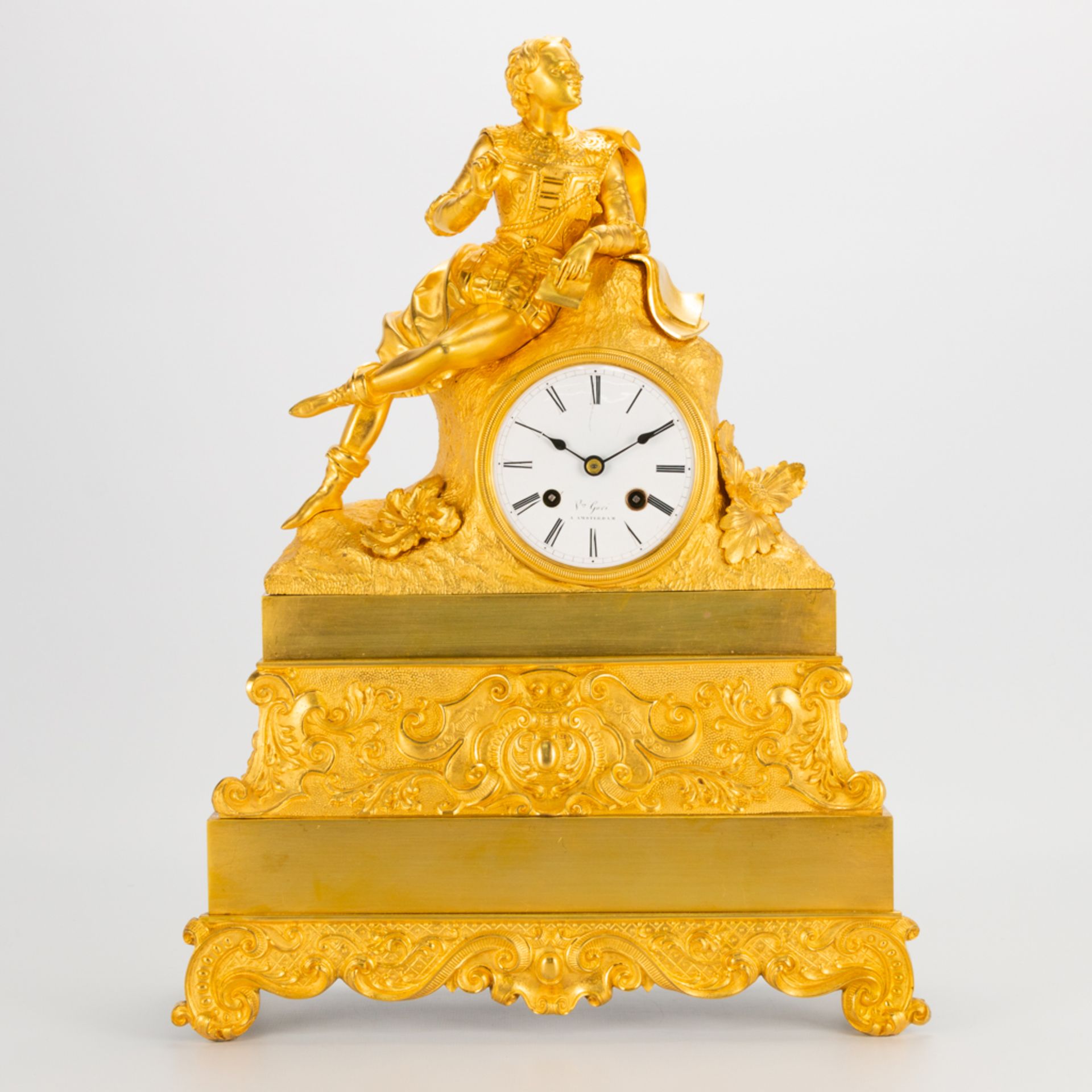 A ormolu gilt table clock made of bronze with a figurine of a noble man, enamel dial and marked Amst