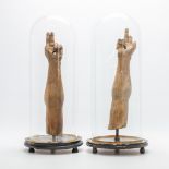 A pair of wood sculptures, 'The arms of Christ', mounted on a stand and displayed under a glass dome