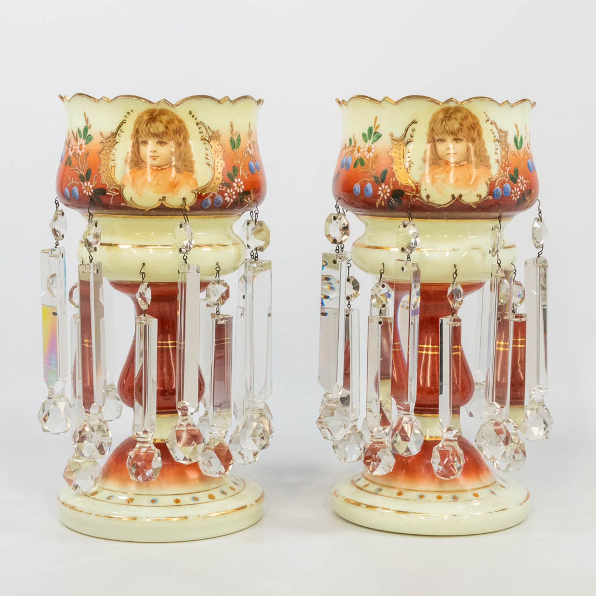 A pair of glass lustres, with hand-painted flowerdecor and printed images of children. (36 x 17,5 cm