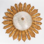 A ceiling lamp in the shape of the sun, made of sculptured wood and glass. The second half of the 20