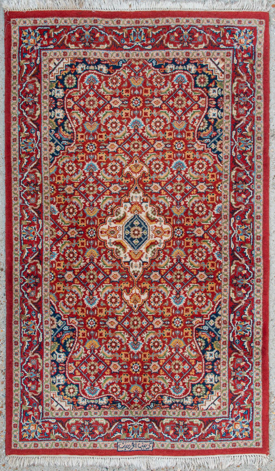 An Oriental hand-made carpet. Kerman with signature. (90 x 155 cm)