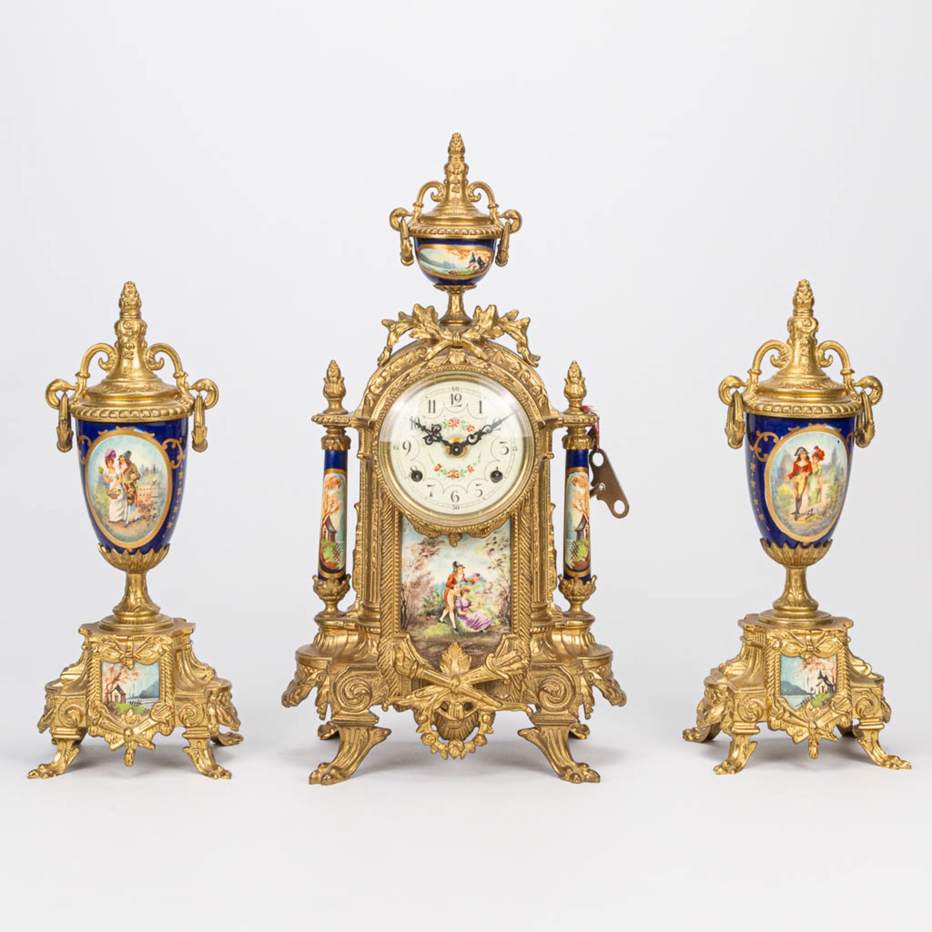 A three piece garniture clock made of bronze with porcelain. The second half of the 20th century. (1