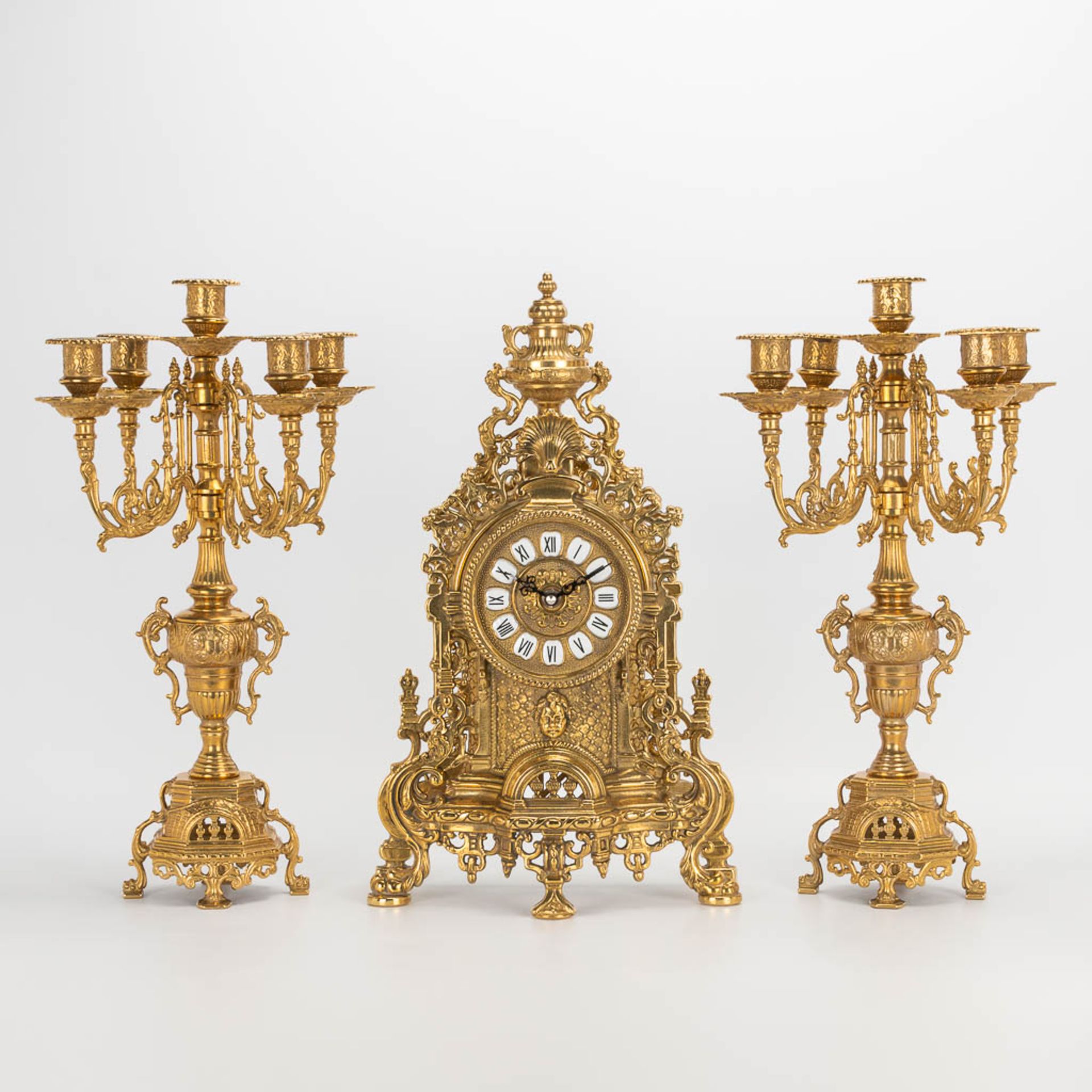 A 3 piece garniture clockset made of bronze, consisting of a clock and 2 candelabra. Battery operate