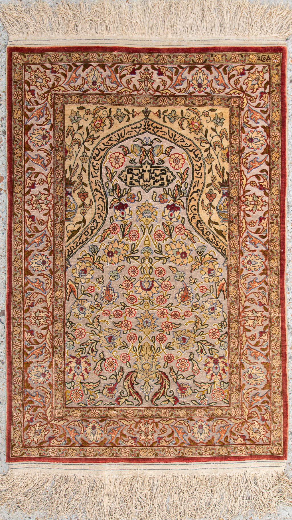 An Oriental hand-made prayer carpet made of silk and finished with gold thread. (58 x 87 cm)
